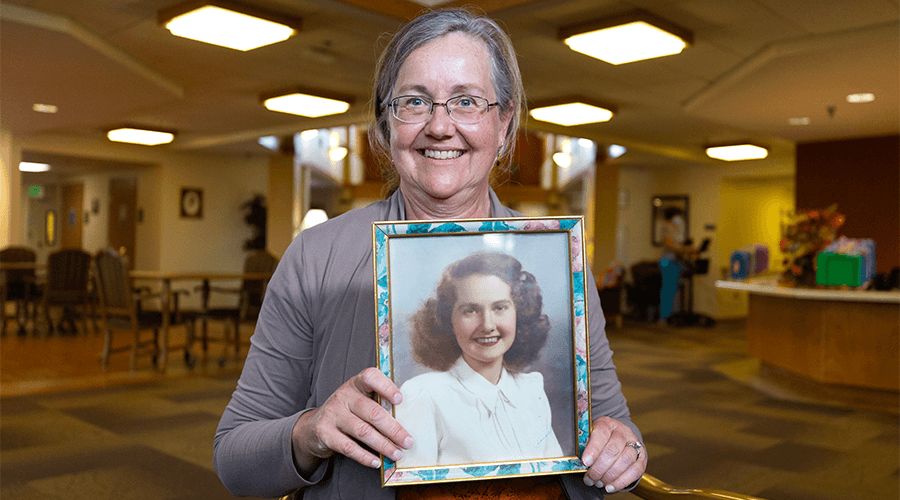Mary Clark smiling and holding a photo of her mother, Beverly