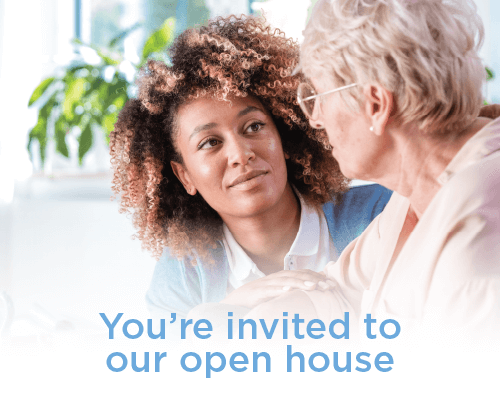 You are invited to our open house. Young caregiver talking with elderly female resident. 